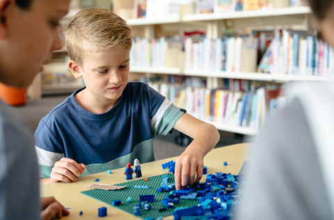Boy playing with blue Lego in Library