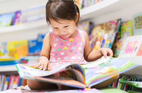 Toddler reading a book in a Library